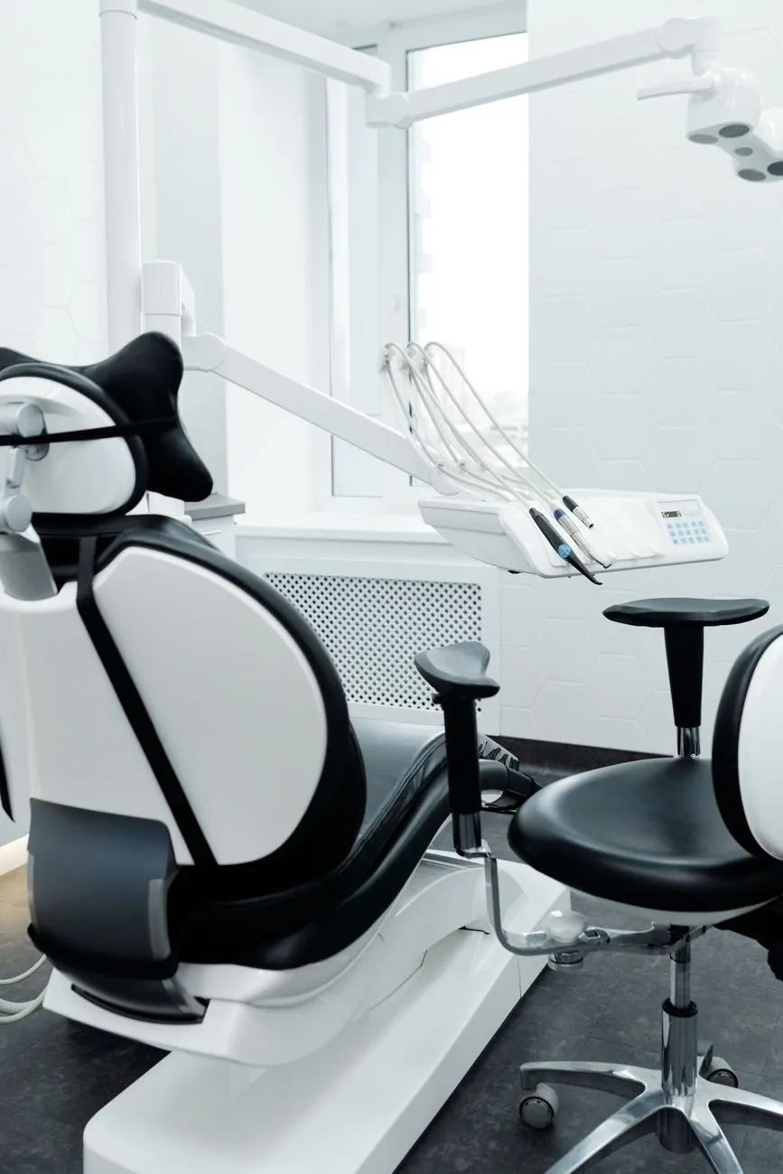 A treatment room with the dental chair upright and a stool beside it
